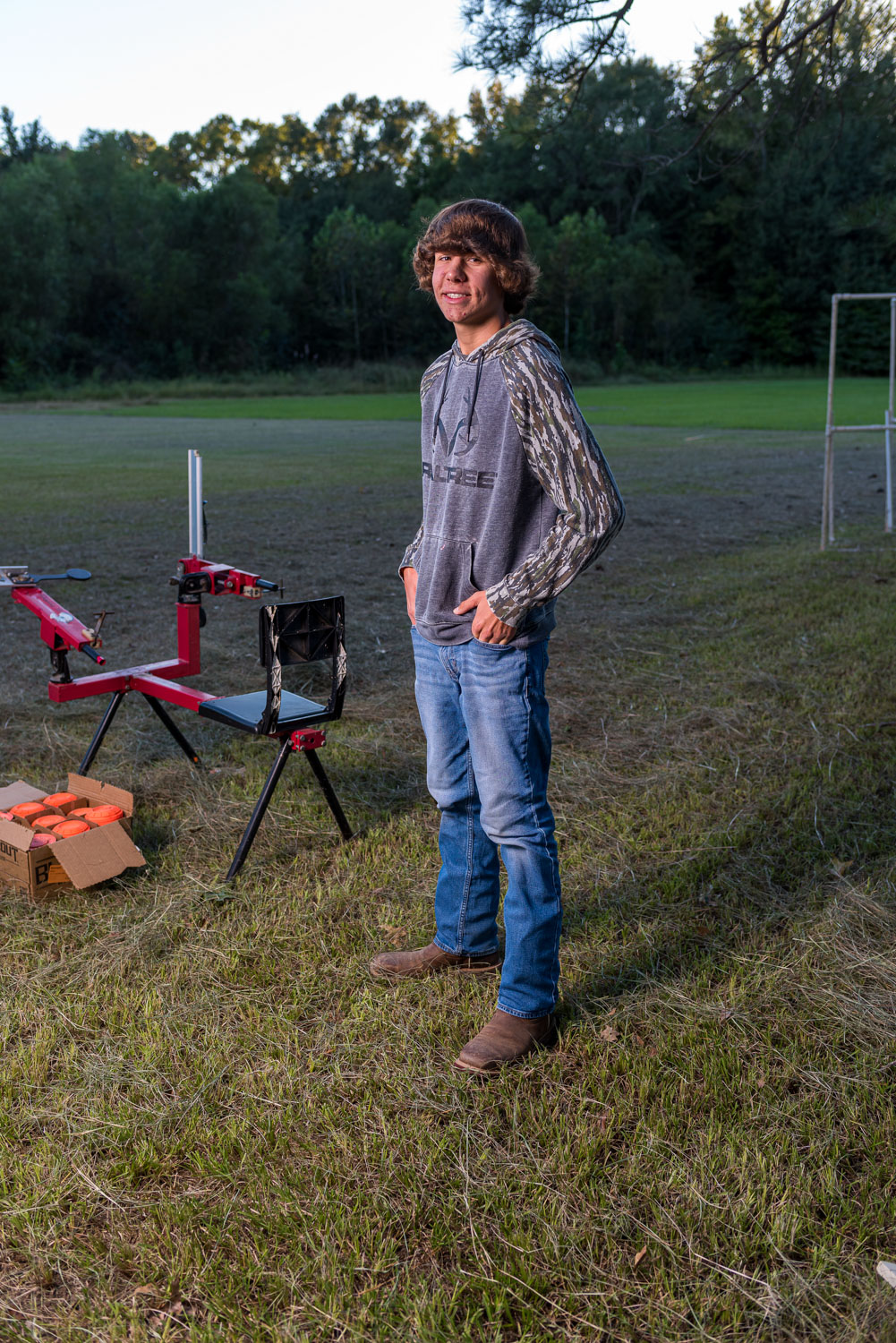 A boy standing beside a sport shooting range smiling.