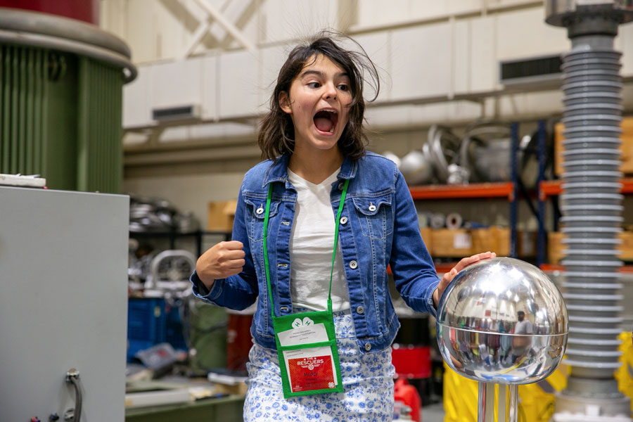 A girl touching an electrical sphere and her hair radiating.