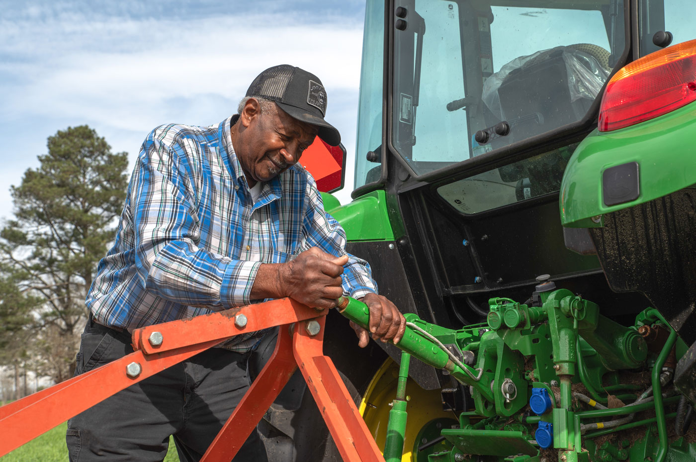 A man working on a tractor hitch.