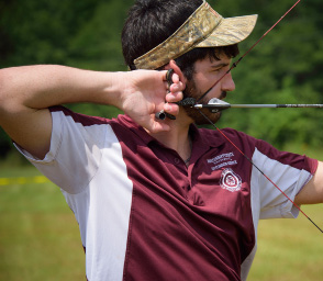 Young man pulling back on a bow.