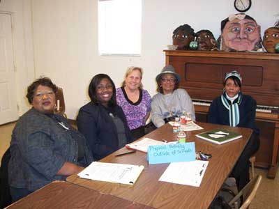 Five women posing around a cluttered table.