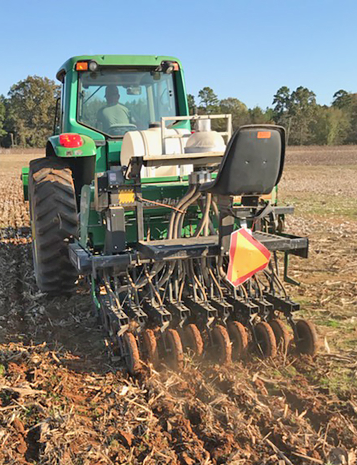 A tractor pulls an implement through an agricultural field.