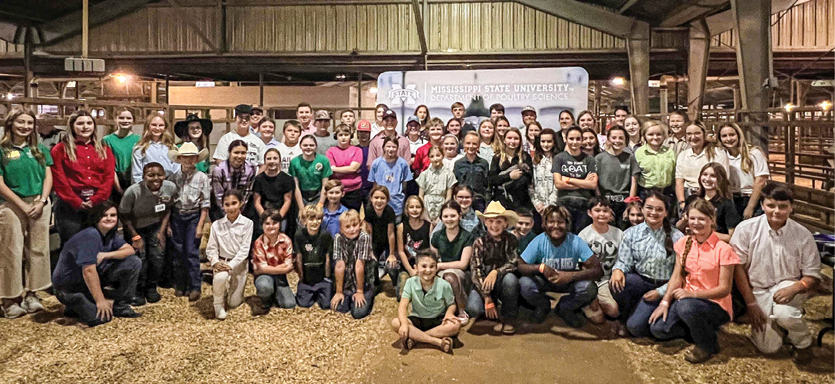 A large group of children and adults are lined up in roughly four rows, posing for the photo. 