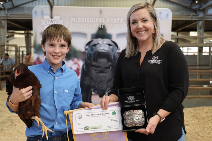 A young boy in a blue shirt proudly holds his award-winning bird while accepting his prize.