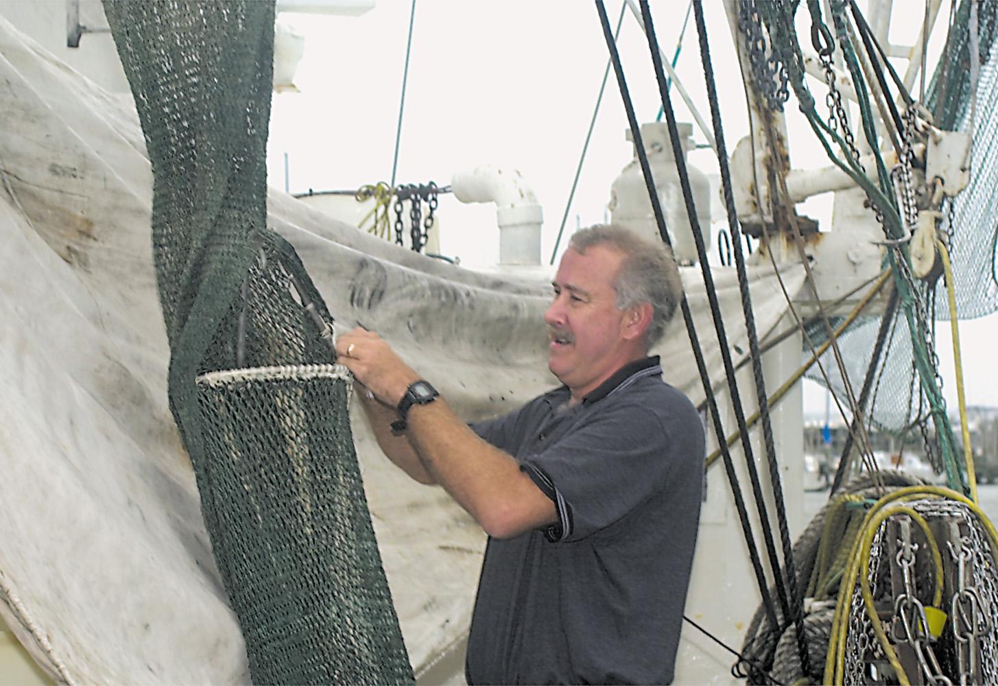 Marine resources specialist Dave Burrage  installs a bycatch reductions device into a shrimp net.