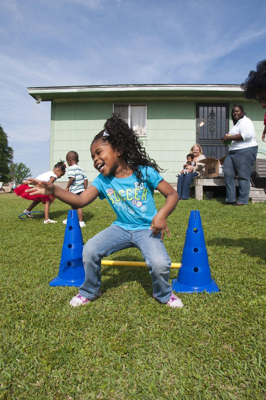 Chloe Gray, 4, a student at Train up a Child Christian Learning Center in Clinton, takes a leap during physical development activities as part of the Nurturing Homes Initiative. (Photo by MSU School of Human Sciences/Alicia Barnes)