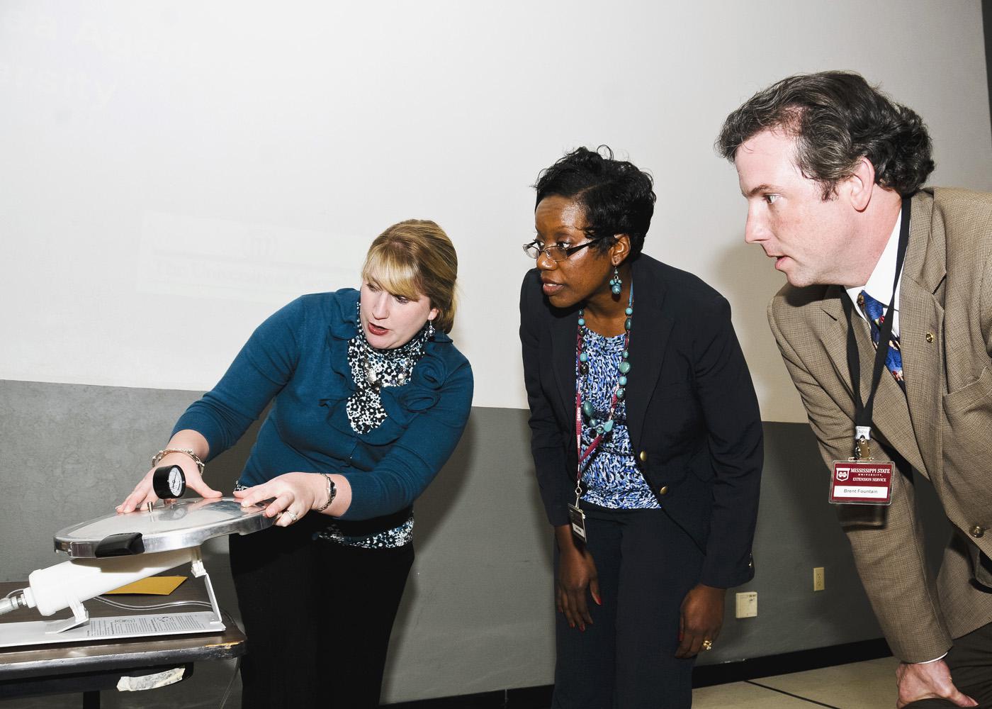 Mississippi State University Extension Service nutrition personnel Pamela Redwine (left) and Brent Fountain, show Lisa Dudley how to test the gauge on a pressure canner. An office associate in Yalobusha County, Dudley and other county support staff members were taught the process so they can meet the needs of clients who come into county offices. (Photo by Scott Corey)