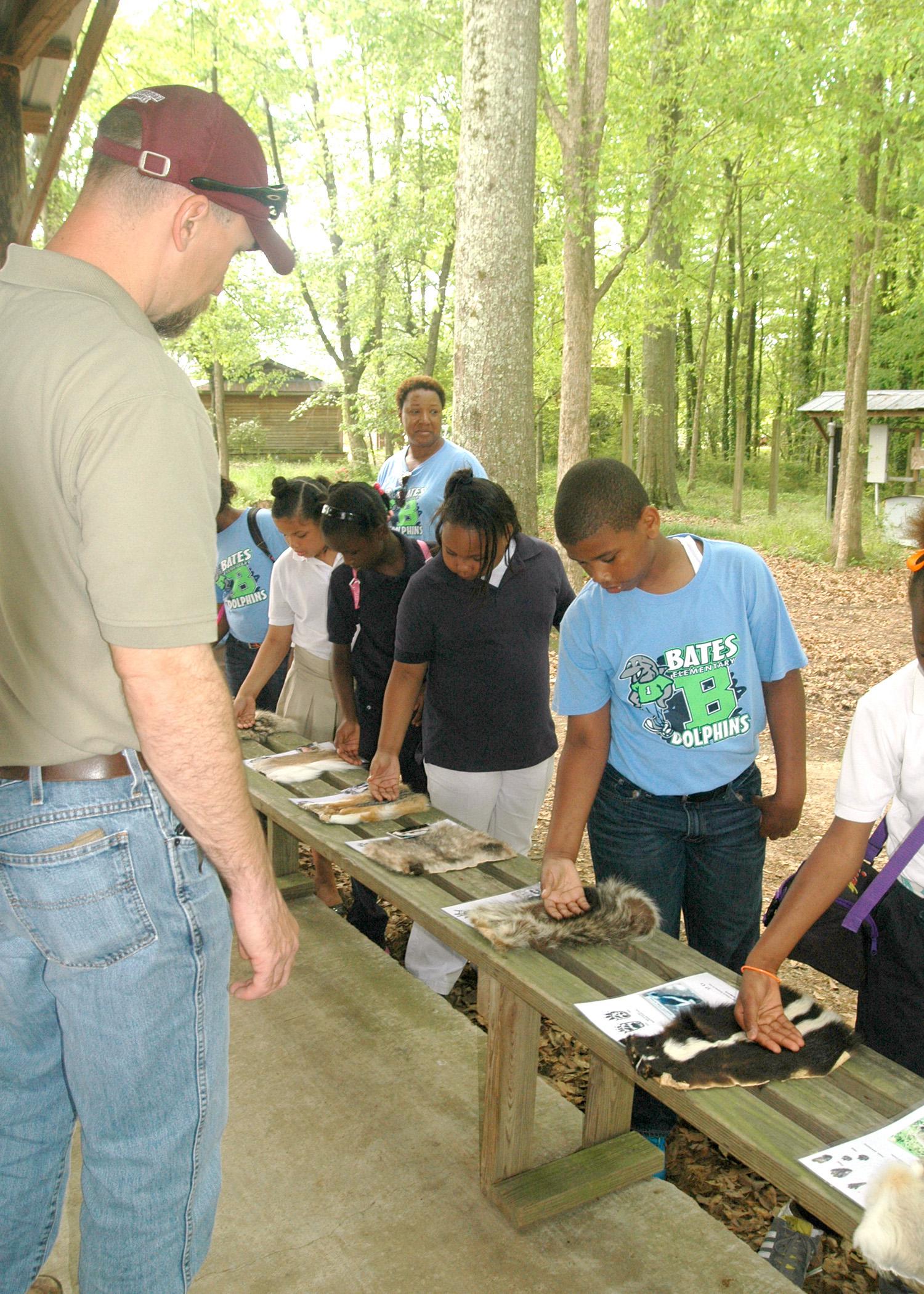Ty Jones, county coordinator with Mississippi State University's Extension Service in Madison County, looks on as Bates Elementary fourth-graders feel the pelts of wild animals native to Mississippi, such as the skunk and raccoon. The display was part of the Extension-sponsored AgVentures at the Mississippi Agricultural and Forestry Museum in Jackson April 16 and 17. (Photo by MSU Ag Communications/Susan Collins-Smith)