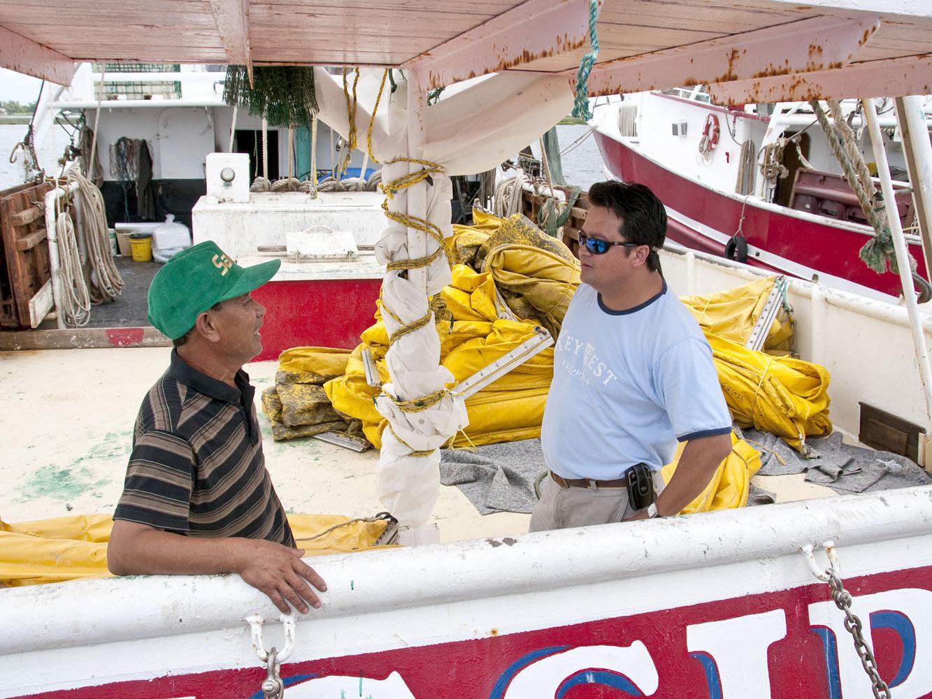 Phat Le, captain of the Mississippi III, discusses cleanup of the Deepwater Horizon oil spill with Extension Fisheries Technician Peter Nguyen. Many fishermen and shrimpers are working as oil spill cleanup contractors for BP. (Photo by Scott Corey)