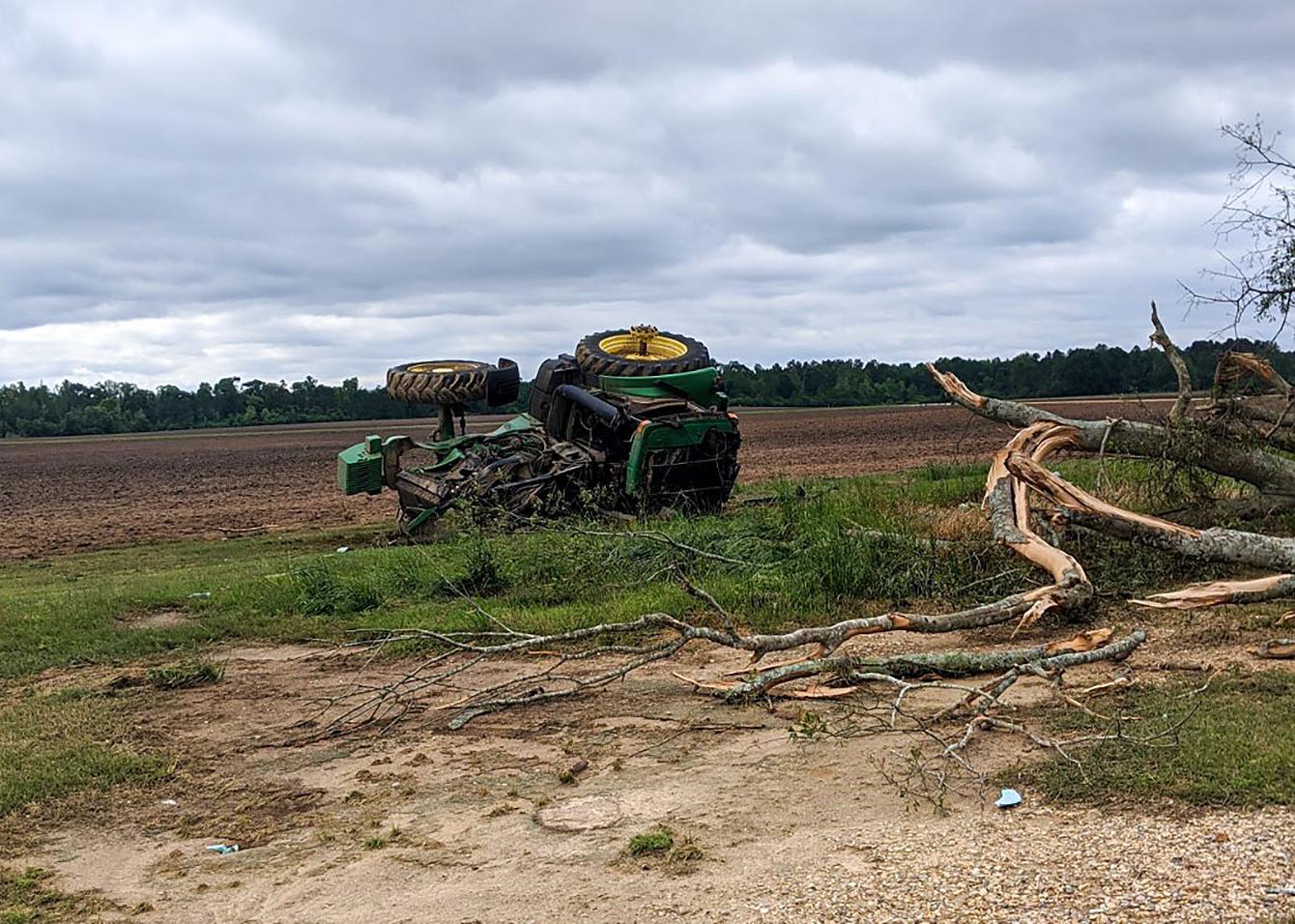 Green tractor flipped on its side in a field.