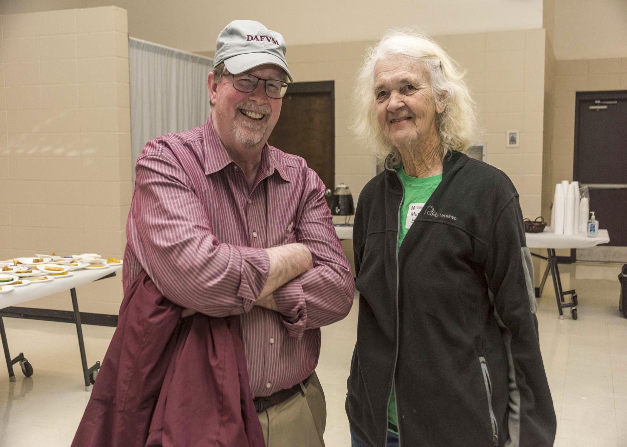 A man and a woman stand together in a meeting space.