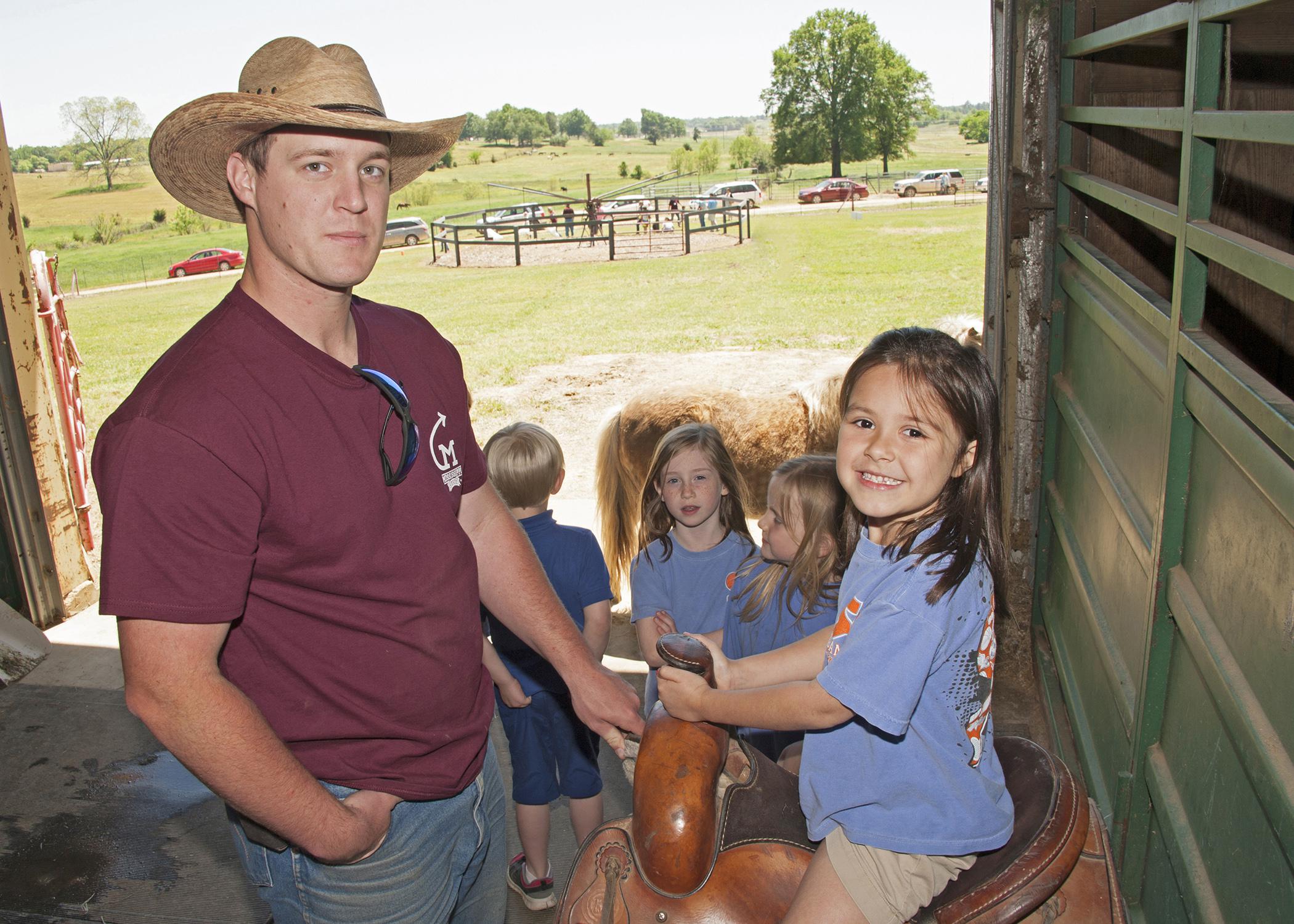 Mississippi State University animal and dairy science major Jacob McCarty of Summit, left, shows Starkville Academy student Abby Edwards how to sit properly in a saddle during Afternoon on the Farm May 1, 2015. The activities took place at the H.H. Leveck Animal Research Center at MSU, commonly called the South Farm, in Starkville. (Photo by MSU Extension Service/Kat Lawrence)