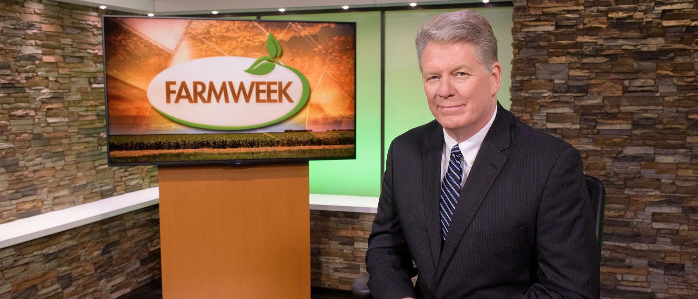 A man sits in TV studio with Farmweek logo on monitor behind him.