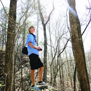 photo of young man with camera in woods