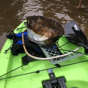 Pieces of trash and rusty metal sitting on the front of a bright green kayak.