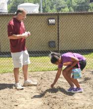Lowndes County Extension Service horticulturist Jeff Wilson measures the appropriate spacing and hands out squash seeds to be planted by military youth such as 10-year-old Keyanna Dooley. They recently planted a Welcome Home Garden for veterans at the Columbus Air Force Base youth center. (Photo by MSU Ag Communications/Scott Corey)