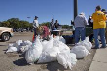 Person in straw hat tying up white trash bags.