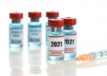 Two medical ampoules of COVID-19 vaccine with a syringe.