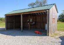 An open wooden shed houses miscellaneous items.