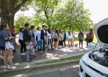 A group of people gather around a vehicle outdoors.