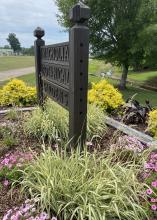 A clump of white and green grass decorates the base of a wooden sign.