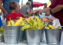 Buckets of peppers stand on a table at a market.