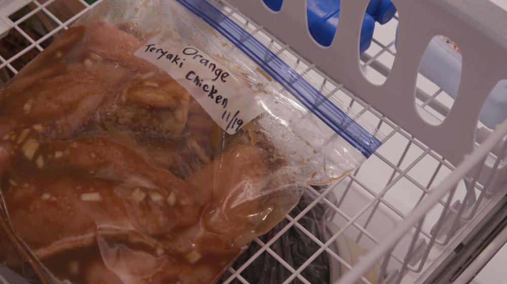 A labeled zip-top bag of Orange Teriyaki Chicken in the freezer.