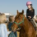 Mary Riley, coordinator for Mississippi State University's 4-H therapeutic riding program, and volunteer Shanna Holder, talk to 9-year-old Elizabeth Howard of Columbus as she sits atop her favorite horse, Bob. Howard's parents, Tommy and Brenda, are donating funds to construct a new therapeutic activity center in West Point. (Photo by Marco Nicovich)