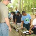 Ty Jones, county coordinator with Mississippi State University's Extension Service in Madison County, looks on as Bates Elementary fourth-graders feel the pelts of wild animals native to Mississippi, such as the skunk and raccoon. The display was part of the Extension-sponsored AgVentures at the Mississippi Agricultural and Forestry Museum in Jackson April 16 and 17. (Photo by MSU Ag Communications/Susan Collins-Smith)