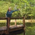 Woman standing on pier in lake holding cup of water