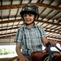 A smiling young man astride a horse and wearing a helmet.