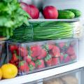 Fruits and vegetables in clear containers in a fridge.