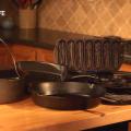 A grouping of various kinds of cast-iron cookware sit on a kitchen counter. 