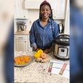 A woman stands in a kitchen with an electric pressure cooker.