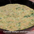  A mixture of small broccoli florets, diced carrots, eggs and cheese baked as a frittata in a large black cast-iron skillet.