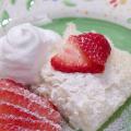 Angel food cake with strawberries, cool whip, and strawberries on a green plate.