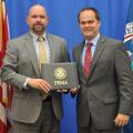 Two men on a stage holding a FEMA certificate and looking at the camera.