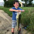 Young boy in blue shirt holding large fish.