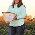 A woman holds a net while standing in a field.