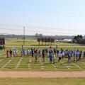 Dozens of people are scattered across a grassy field marked into squares.