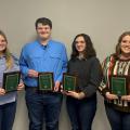 Four teenagers hold plaques.