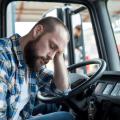 Tired man rests his head in a truck cab.