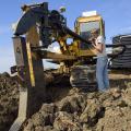 Dylan Yost feeds plastic tubing into equipment that buries drain tile in a deep furrow in fields. This Noxubee County field was being tiled Nov. 8, 2016. (Photo by MSU Extension Service/Kevin Hudson)