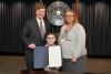 Three individuals pose with a newly signed proclamation.