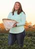 A woman holds a net while standing in a field.