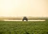 A tractor with a boom arm sprays crops.