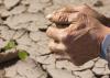 Hands clasped together over a dry field.